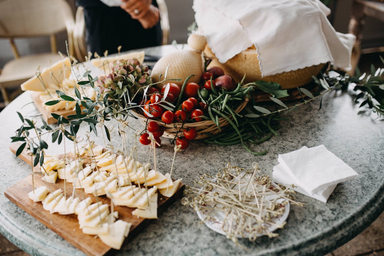 Serving of sliced cheese and cherry tomatoes on a marble table with fresh herbs.
