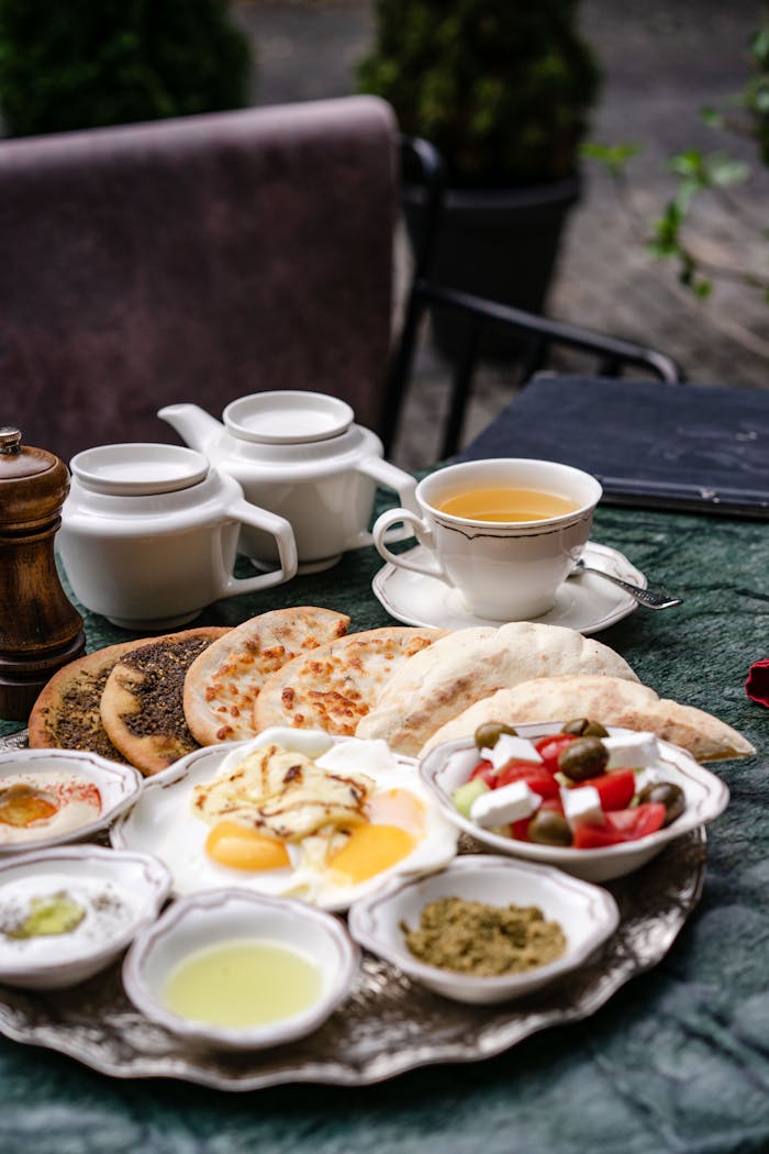 A sumptuous Middle Eastern breakfast spread on an outdoor table with various dishes and a tea set.
